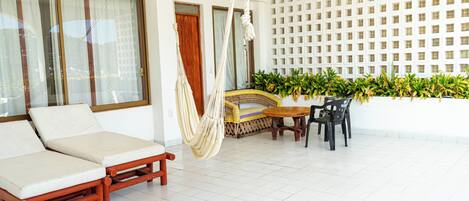 A room with a sofa, a hammock, a table, and chairs.
