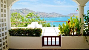 A balcony with a view of the sea and hills.