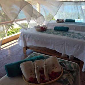 A room with two beds, each covered with white linens and a green floral pattern. There are towels and bottles on the beds, and a basket of rose petals on the floor. - Catalina Beach Resort (Zihuatanejo)