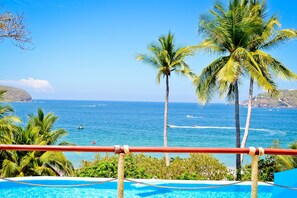 A pool with a view of the ocean and palm trees. - Catalina Beach Resort (Zihuatanejo)