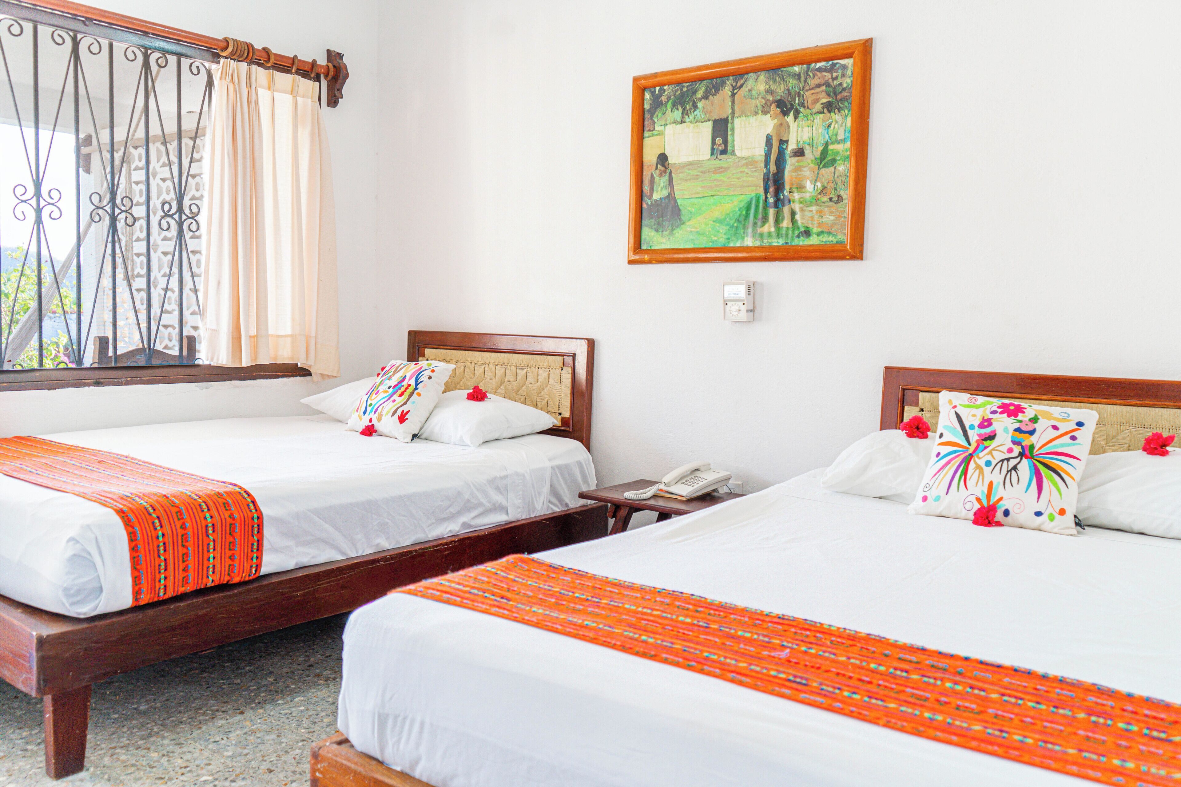 Two single beds with wooden frames, white bedding, and orange decorative borders.