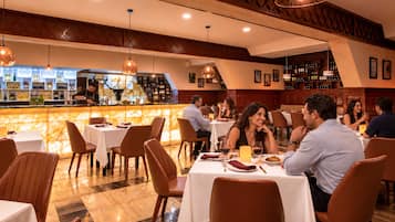 A restaurant with a bar area, multiple tables, and chairs.