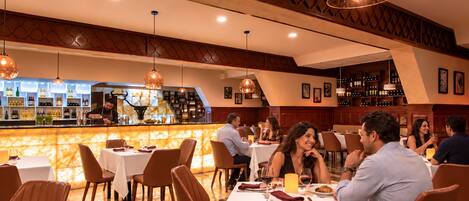 A restaurant with a bar area, multiple tables, and chairs.