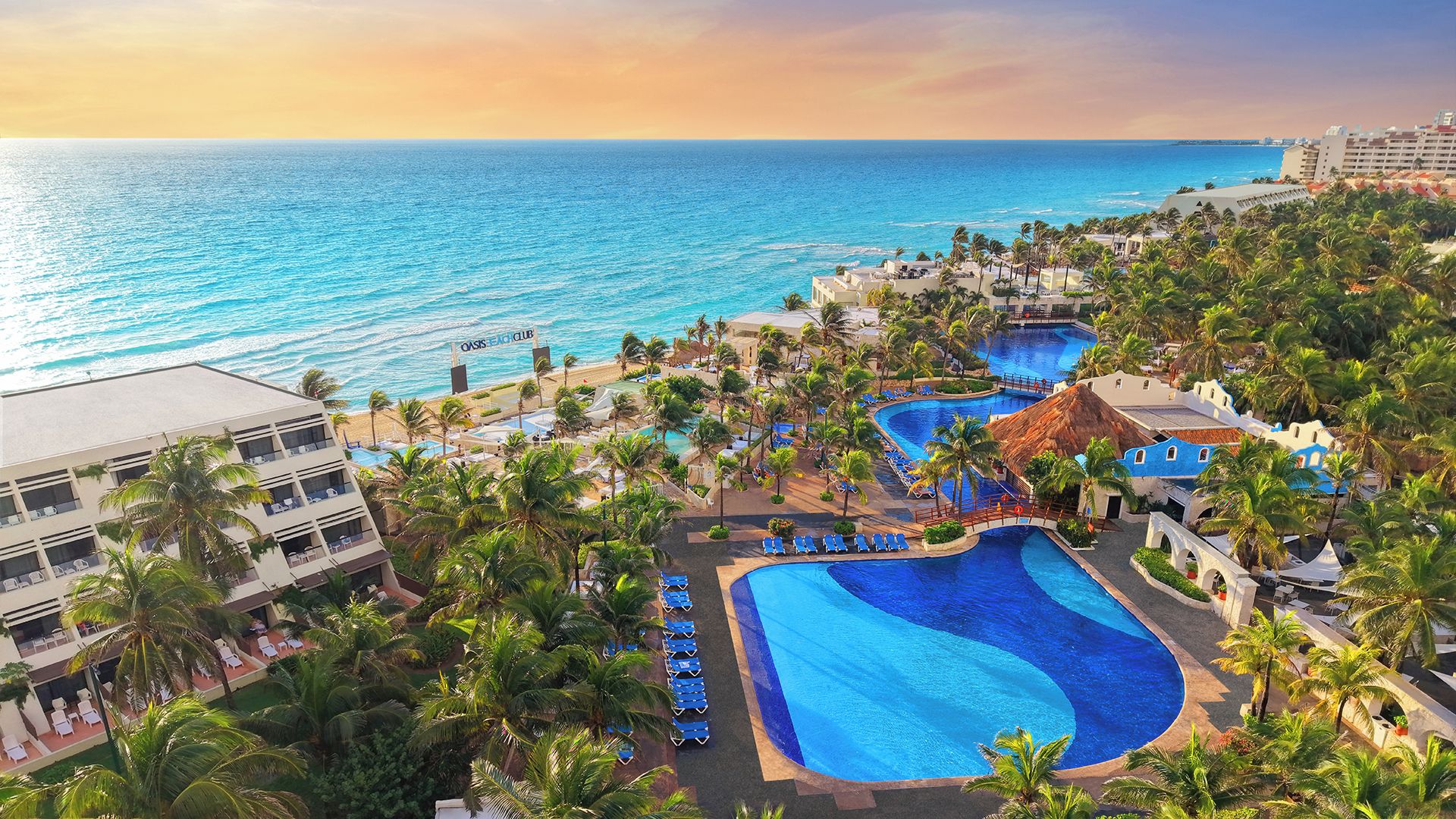 A resort with a large pool, palm trees, and a view of the ocean.