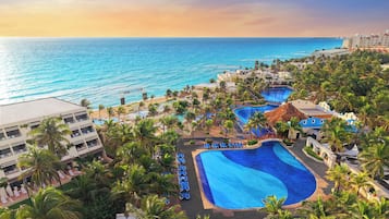 A resort with a large pool, palm trees, and a view of the ocean.