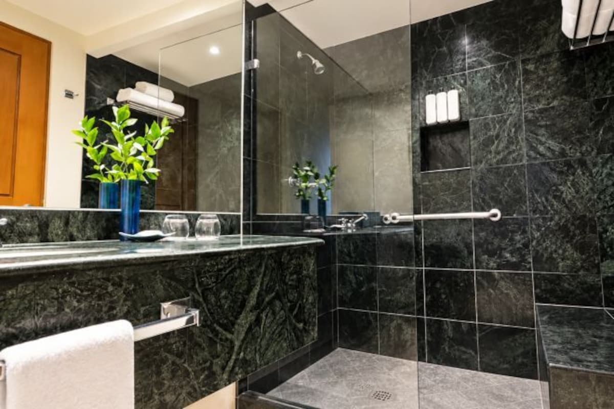 A modern bathroom with a marble countertop, a glass shower enclosure, and a towel rack.