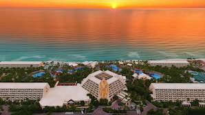 A resort with multiple swimming pools, a central building with a distinctive design, and a beach in the background. - The Grand Oasis Cancun - All Inclusive (Cancun)
