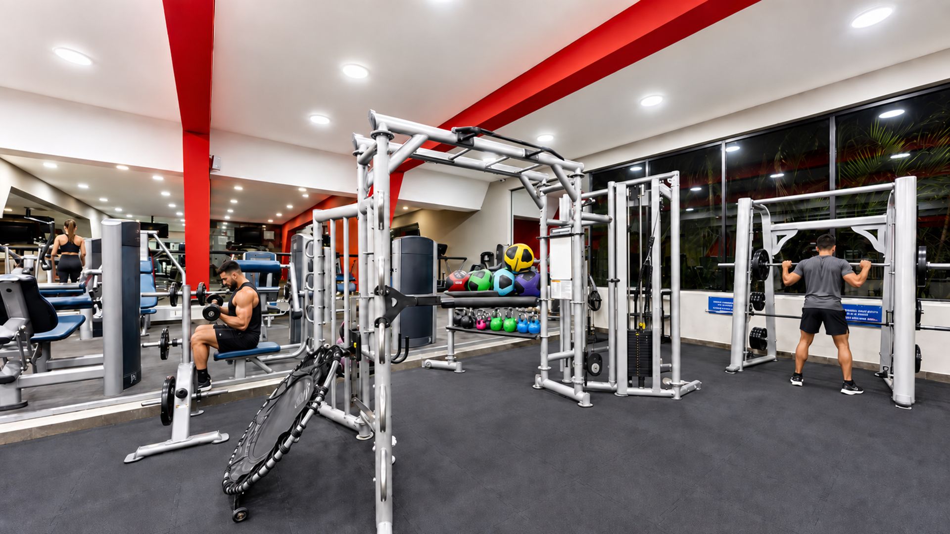 Un gimnasio con diversos equipos de ejercicio, incluyendo máquinas de pesas, bancos y pesas libres.