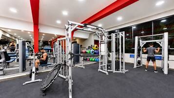 Un gimnasio con diversos equipos de ejercicio, incluyendo máquinas de pesas, bancos y pesas libres.