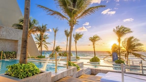 A resort pool area with multiple pools, palm trees, and a view of the ocean at sunset. - The Grand Oasis Cancun - All Inclusive (Cancun)