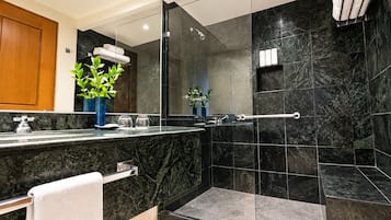 Un baño moderno con encimera de mármol, cabina de ducha con mampara de vidrio y un perchero para toallas.