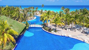 Ein Resort mit großem Schwimmbad, Palmen und Blick auf den Ozean.