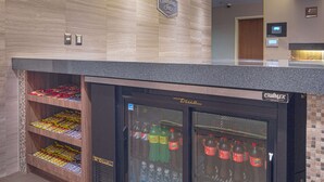 A hotel reception area with a counter, a refrigerated display case with beverages, and a shelf with snacks. - Hampton Inn by Hilton Monterrey/Galerías-Obispado (Monterrey)