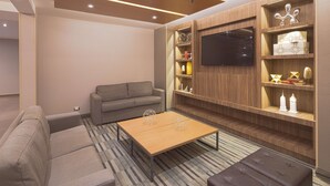 A modern living room with a sofa, a coffee table, and built-in shelving with decorative items. - Hampton Inn by Hilton Monterrey/Galerías-Obispado (Monterrey)