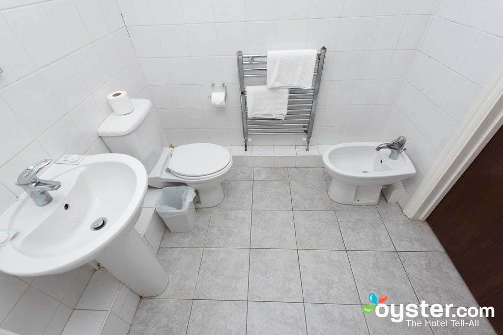 A small, clean bathroom with a sink, toilet, bidet, and towel rack.