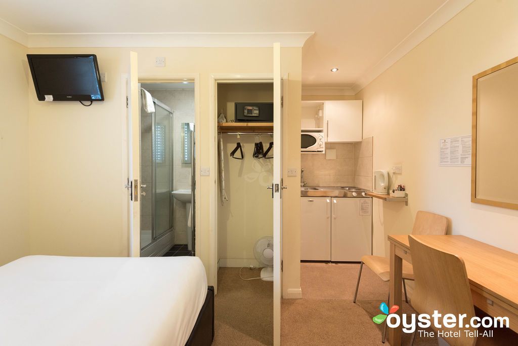 Habitación de hotel con cama, escritorio, kitchenette y baño.