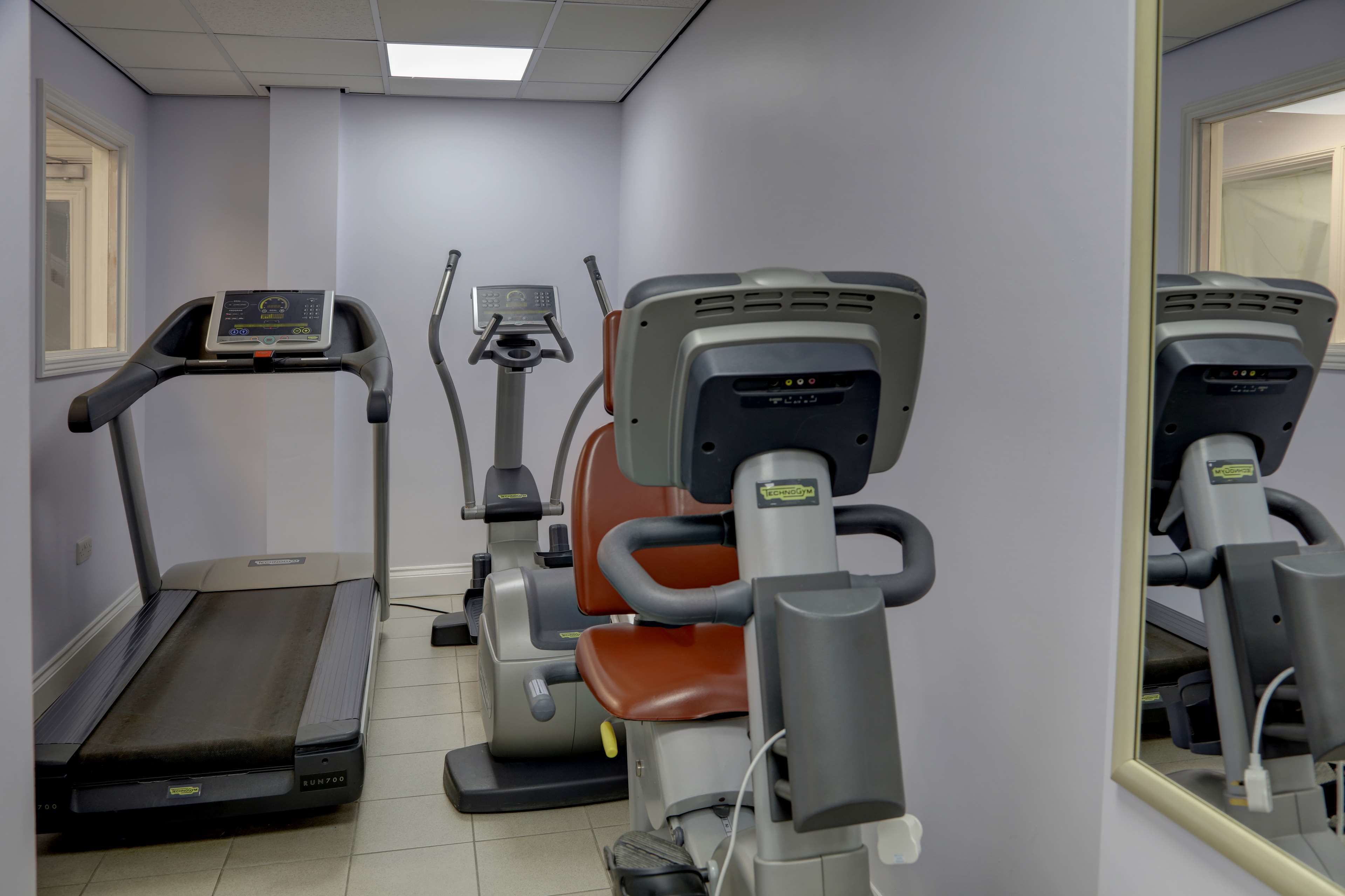 Une salle de sport équipée de tapis de course, de vélos elliptiques et d’appareils de musculation.
