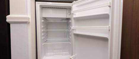 A compact kitchen with a built-in microwave and a refrigerator.