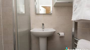 A bathroom with a glass shower enclosure, a white sink, and a mirror with lights.