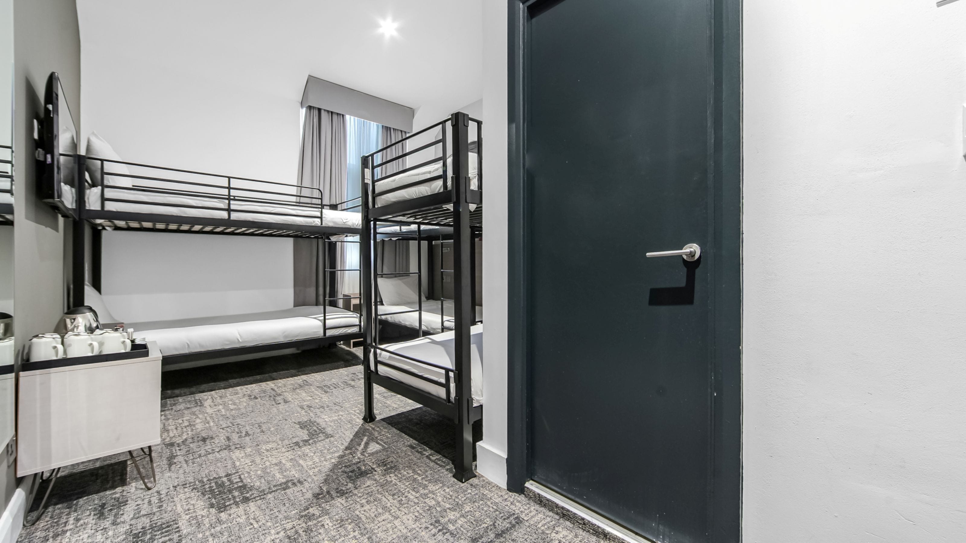 Une chambre avec un lit superposé, un bureau et une porte.