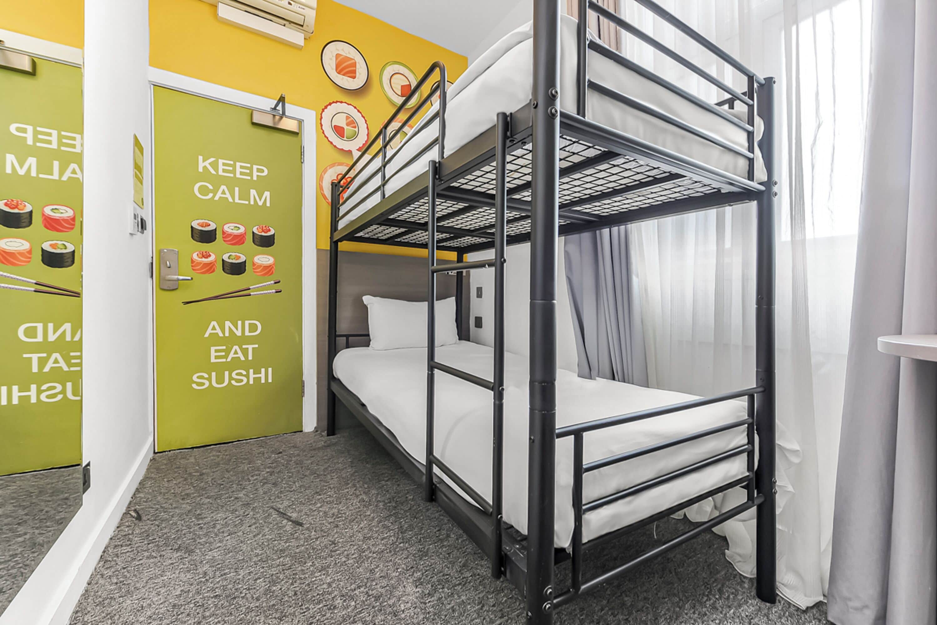 A bunk bed room with a green door and a wall with sushi illustrations.