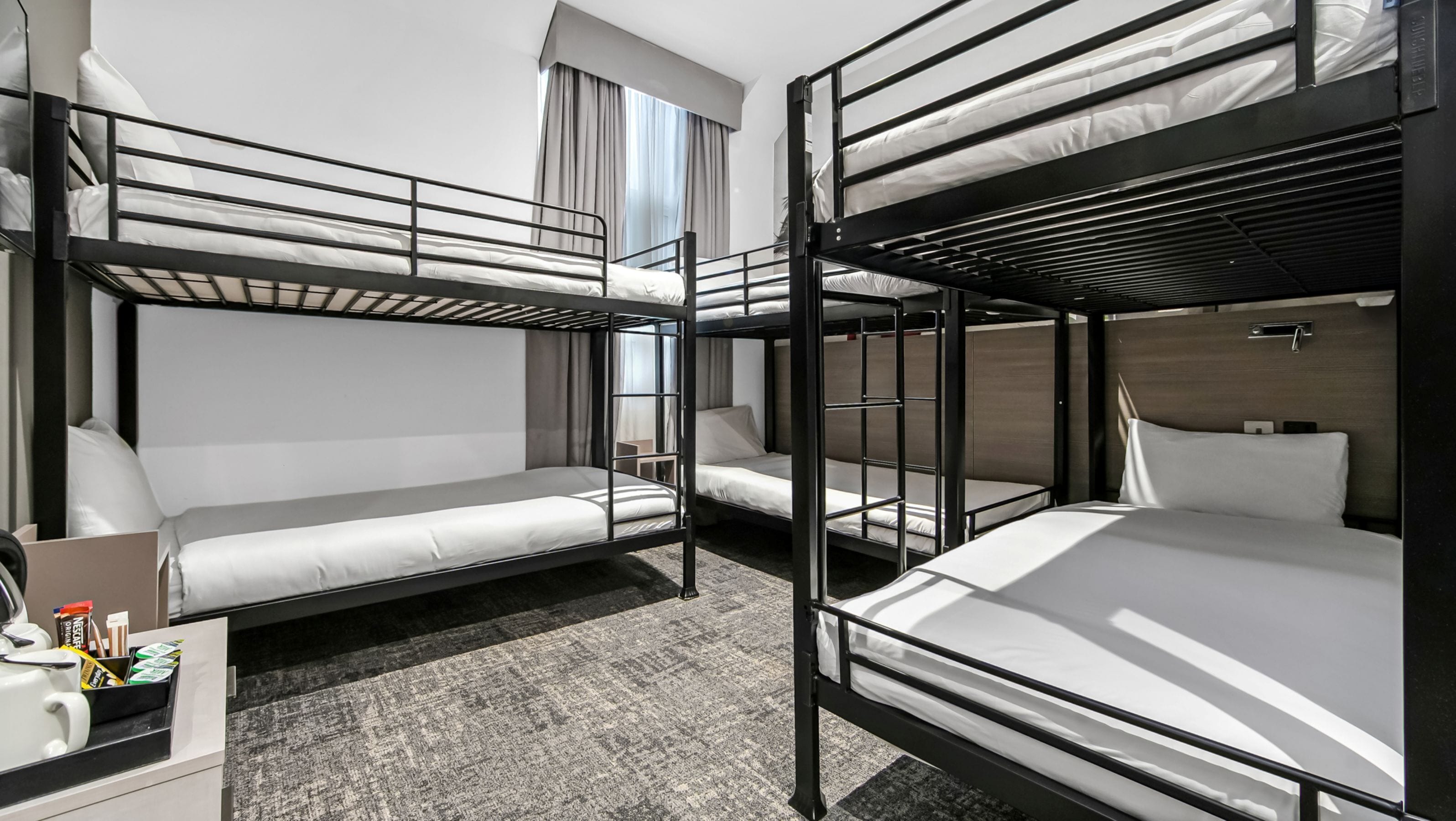 A bunk bed room with a desk and a nightstand.