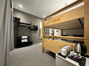A hotel room with a bunk bed, a TV, a coffee maker, and a small table with a remote control. - Heeton Concept Hotel Kensington (London)