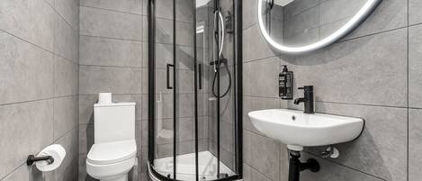 A modern bathroom with a glass-enclosed shower, a toilet, and a sink.