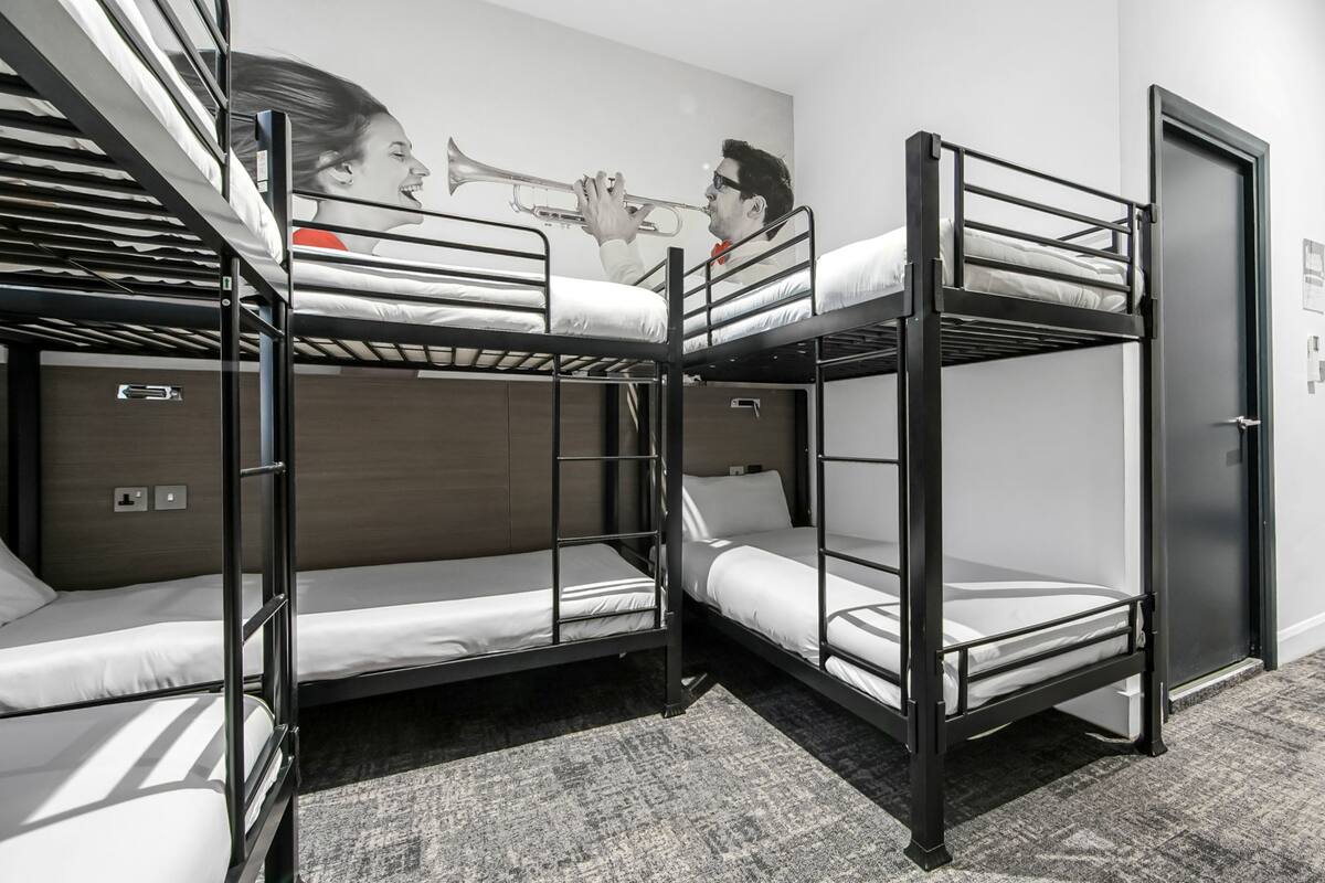 Een slaapkamer met stapelbed, muurschildering, een deur en een vloerbedekking.