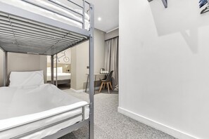 A hotel room with a bunk bed, a desk with a chair, and a small table with cups. - Heeton Concept Hotel Kensington (London)