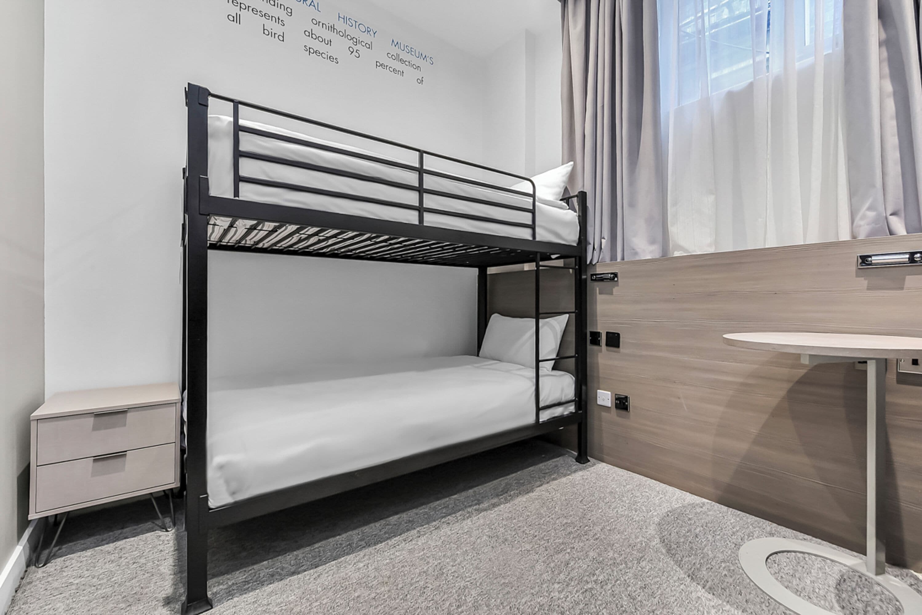 A bunk bed room with a small desk and a nightstand.