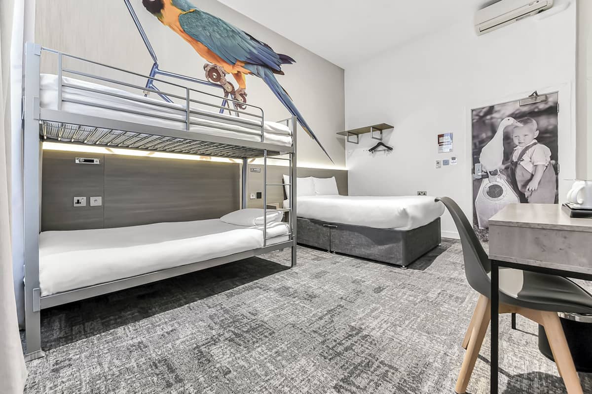 Een hotelkamer met stapelbedden, een bureau en een stoel.