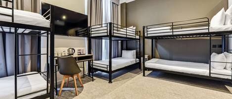 A hotel room with bunk beds, a desk, a chair, and a TV.