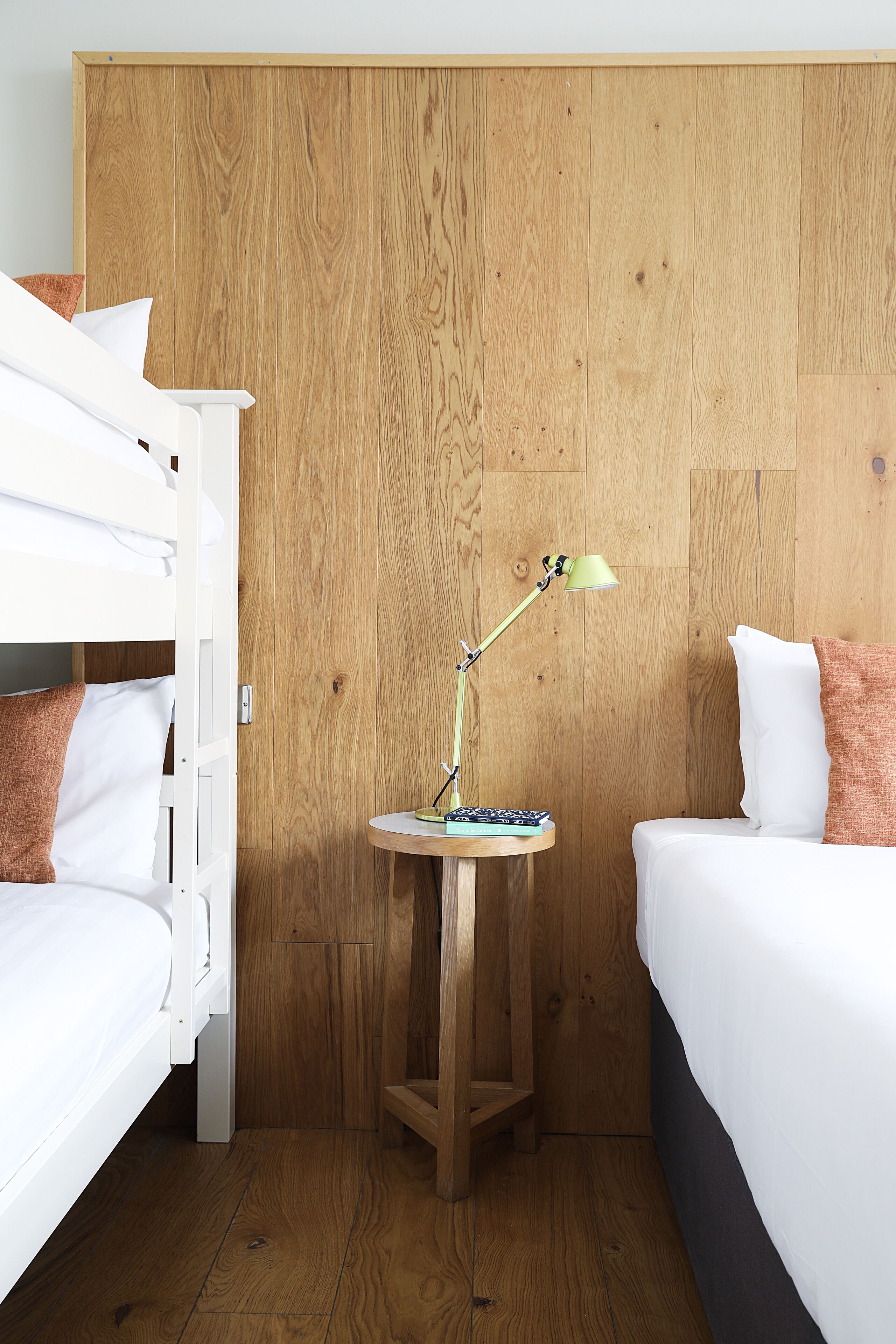 A room with a bunk bed, a bedside table with a lamp, and a single bed.