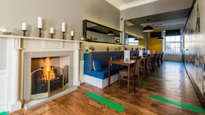 Un intérieur moderne avec une cheminée, un coin repas et un espace détente agrémenté d’un canapé bleu.