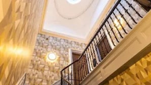 Un escalier avec un mur orné d’un motif géométrique et une lucarne circulaire.
