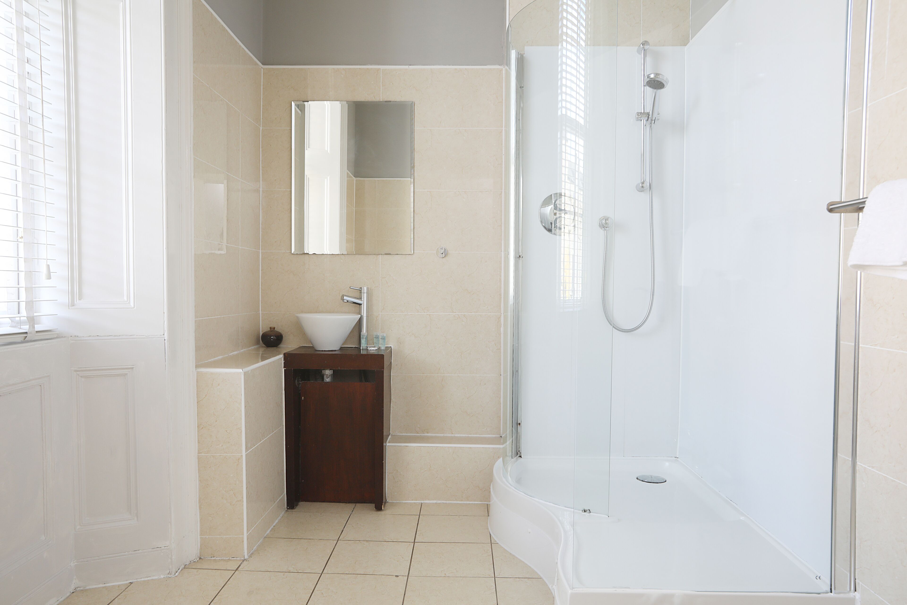 A modern bathroom with a glass-enclosed shower, a sink with a mirror above, and a wooden cabinet.