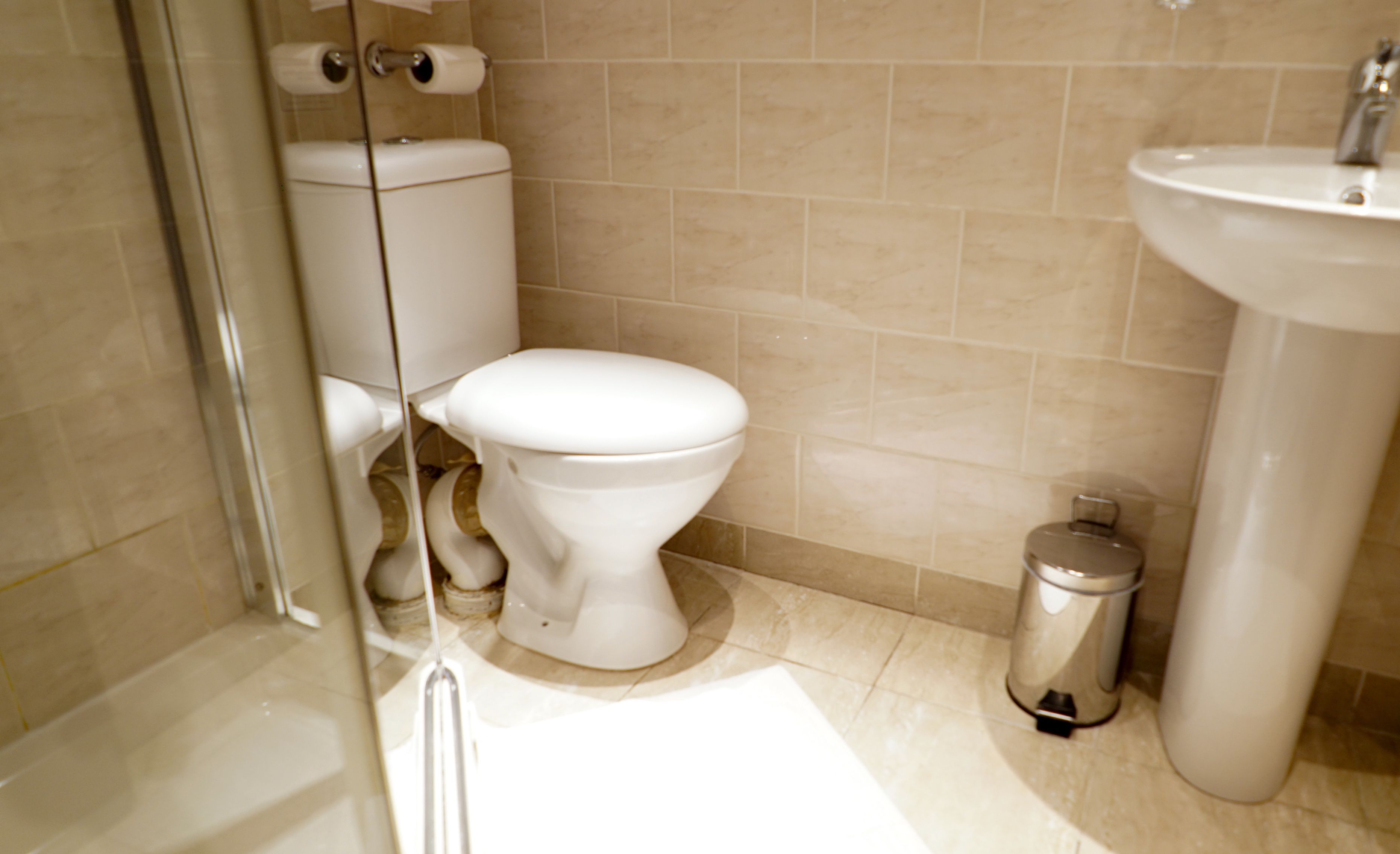 A bathroom with a toilet, sink, and trash can.
