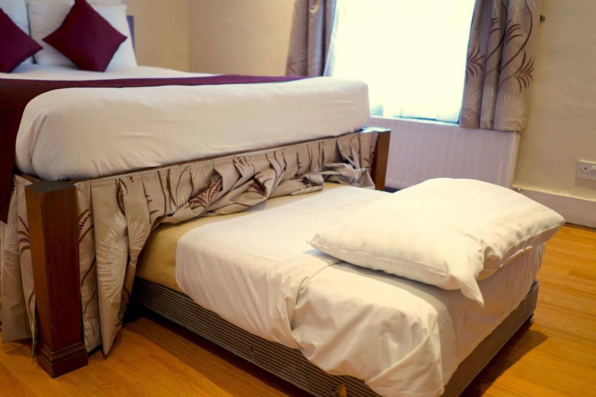 A bed with a white comforter and a patterned throw blanket.