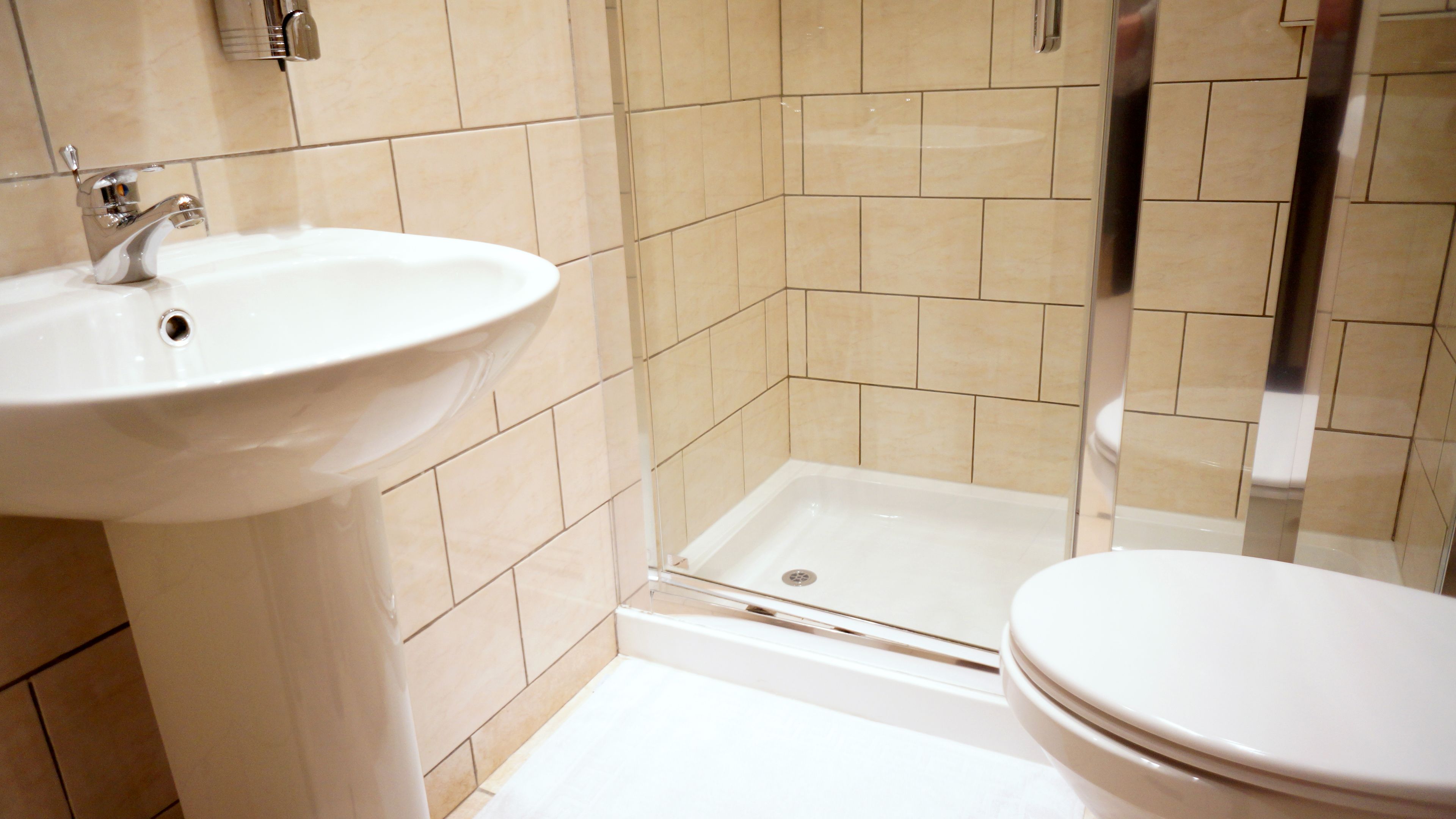 Un baño con lavamanos blanco, ducha e inodoro.