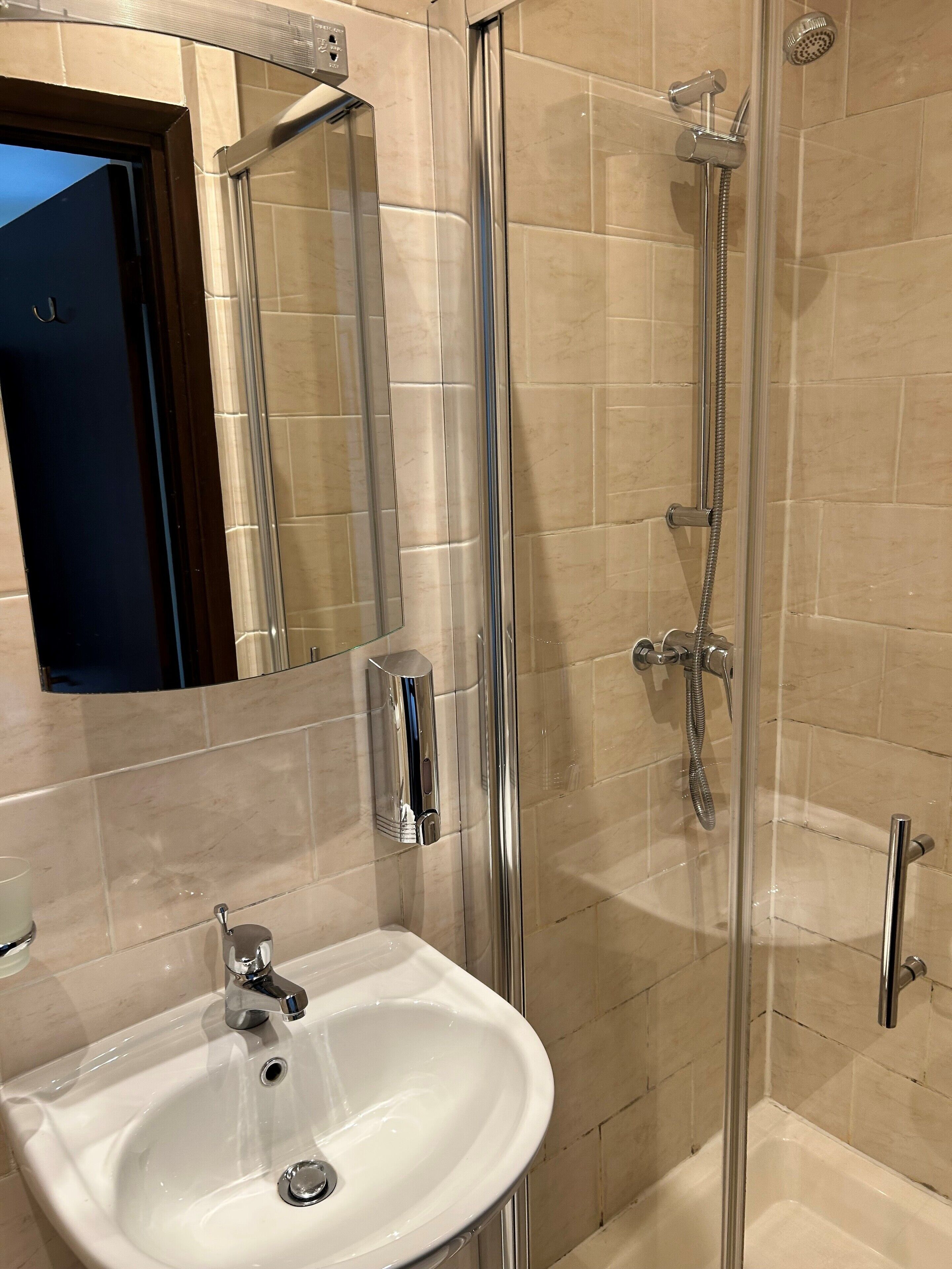 Un baño con ducha de vidrio, lavamanos blanco y espejo.
