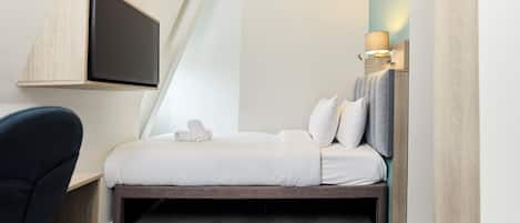 Una habitación de hotel moderna con una cama, un escritorio y un televisor montado en la pared.