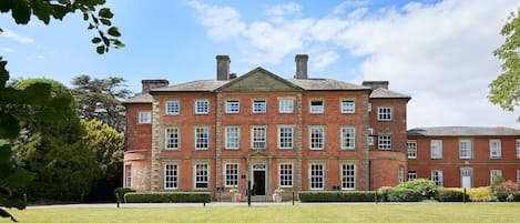 A large, red brick building with a symmetrical facade, multiple windows, and a central entrance.