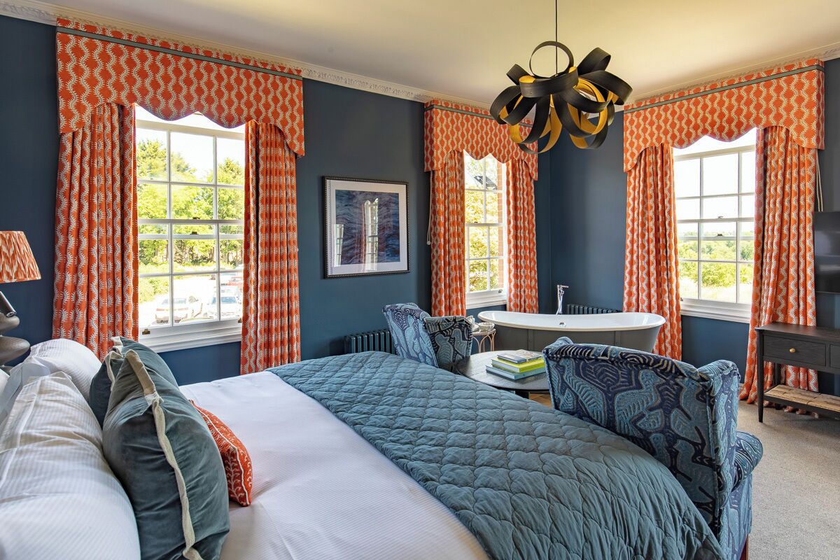 A bedroom with a large bed, a round table, and a bathtub.