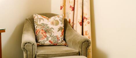 A corner armchair with a floral cushion and a matching ottoman.
