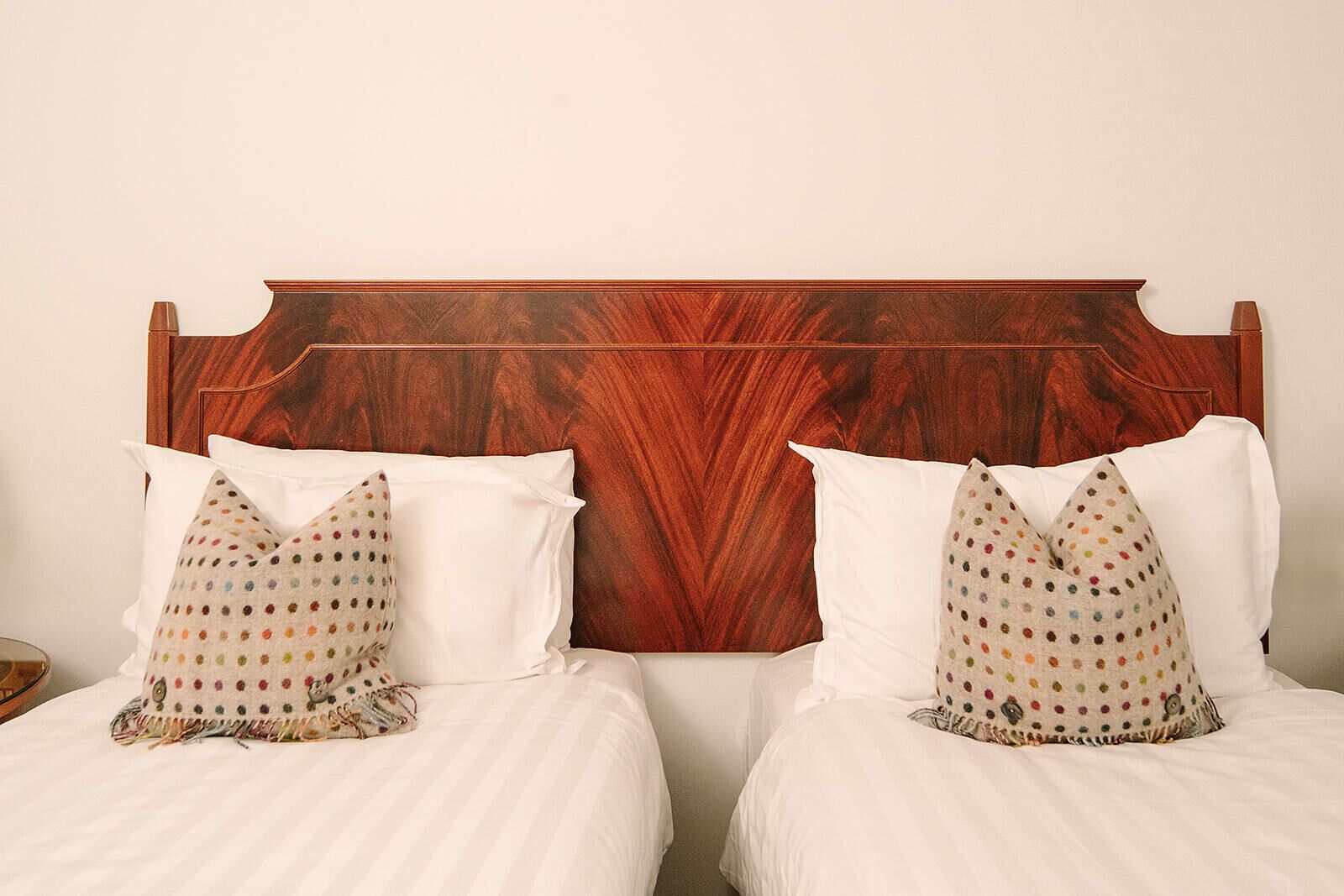 A double bed with white bedding and two pillows with a polka dot pattern.