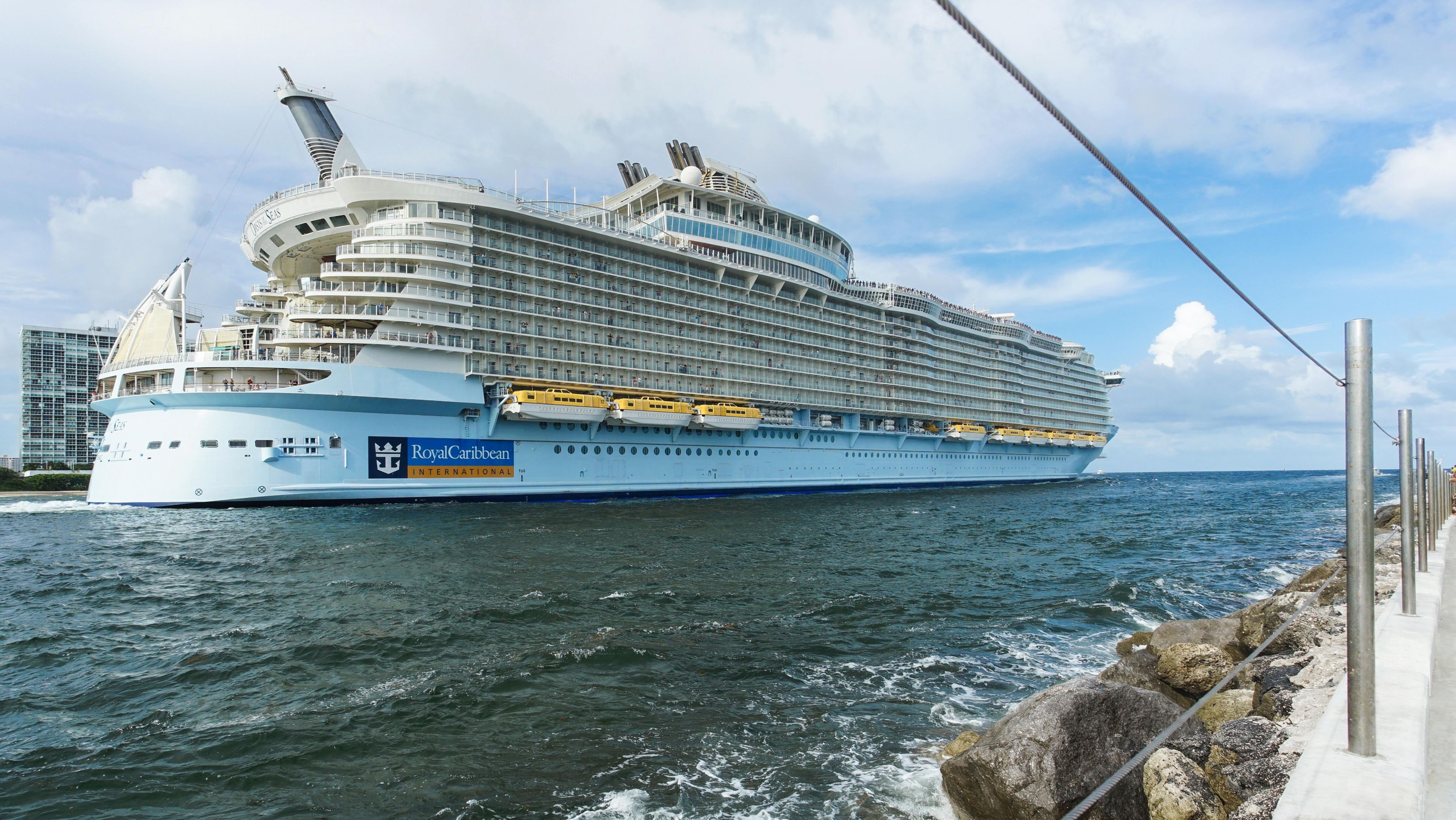 Un grand navire de croisière était amarré dans un port, et on pouvait voir ses nombreux ponts ainsi que ses canots de sauvetage.
