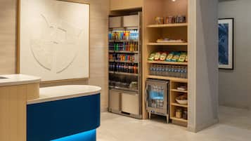 A reception area with a counter, a refrigerator stocked with beverages, and a wall-mounted artwork.
