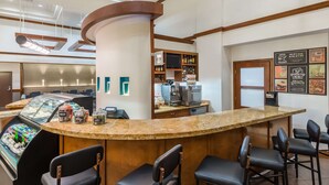 A bar area with a curved granite countertop, bar stools, and a refrigerated display case with beverages. - Hyatt Place Atlanta/Duluth/Johns Creek (Johns Creek)