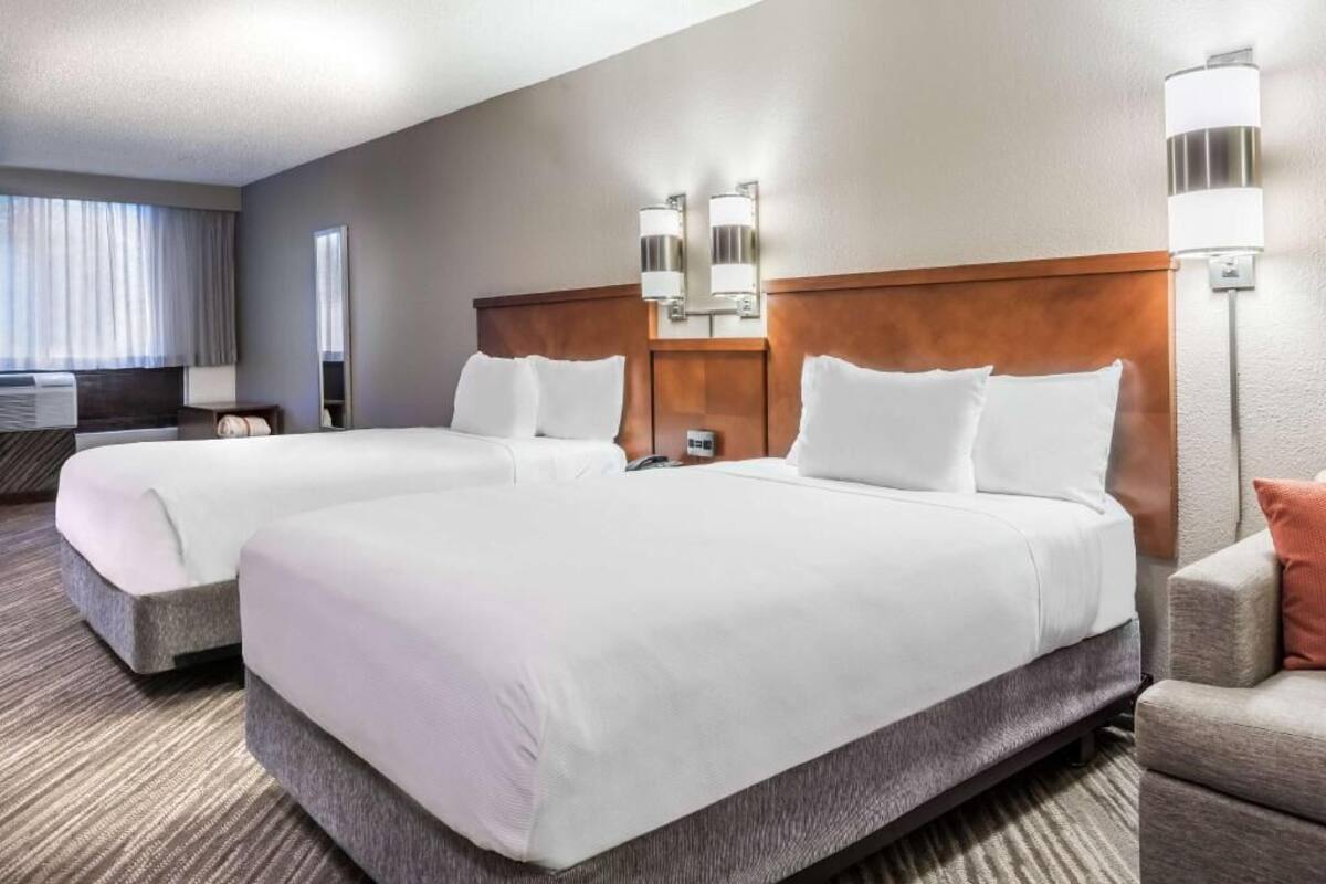Une chambre d’hôtel avec deux lits, un canapé, un bureau et une lampe.